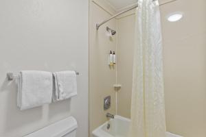 uma casa de banho branca com um chuveiro e um WC. em Garnet Inn & Suites, Morehead City near Atlantic Beach em Morehead City