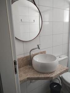 y baño con lavabo blanco y espejo. en TOP 3 suítes NOVO em Capão, en Capão da Canoa