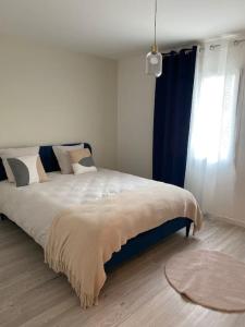 a bedroom with a large bed with a blue curtain at Maison By Sana proche du lac in Châtellerault