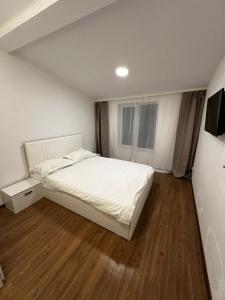 a bedroom with a white bed and a wooden floor at Stone Residence in Braşov