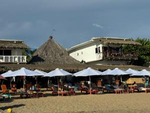 Che Zipolite Hostel & Naked Beach Club في زيبوليت: مجموعة طاولات وكراسي مع مظلات على الشاطئ