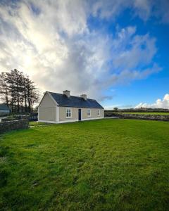 a white house in a field with a green yard at Killawalla Cottage, Westport. in Westport