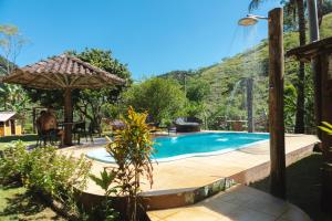a swimming pool with a table and an umbrella at Peniel do Sana Guest House in Sana