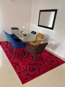 mesa de comedor con sillas y alfombra roja en Four m luxury Apartment., en Kitwe