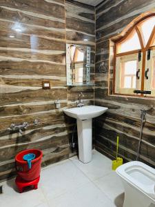 HOTEL MERLIN PALACE في سريناغار: حمام بجدران خشبية ومغسلة ومرحاض