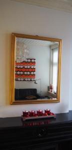 a mirror on a wall with red bowls on a fireplace at Het Zwolse Huisje in Zwolle