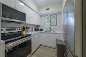 una cucina con armadi bianchi e frigorifero in acciaio inossidabile di Apartment in Calle Ocho a Slice of Little Havana a Miami