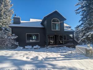 una casa negra en la nieve con árboles en Stay in Evergreen - Denver Mountain Escape en Evergreen