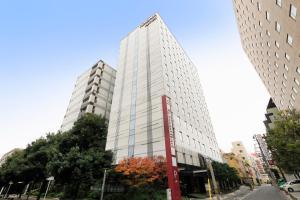 a tall white building with a sign in front of it at Richmond Hotel Utsunomiya-ekimae Annex in Utsunomiya