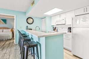 a kitchen with blue walls and a counter with stools at Sunrise Suites Barbados Suite #204 in Key West