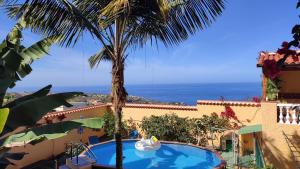 un resort con una palma e una piscina di Casa" VISTAS AL TEIDE" mar Piscina privada parking cubierto gratuito en las instalaciones a La Victoria de Acentejo