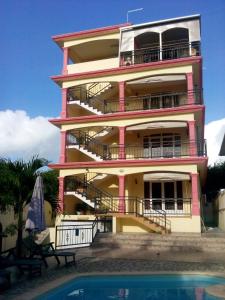 a pink building with a pool in front of it at Rama Villas Mauritius in Trou aux Biches