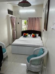 a bedroom with a bed with two chairs and a window at 2BHK Chandra Jyoti Villa NIT Garden Nagpur in Nagpur