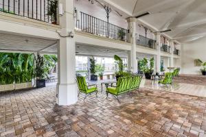 un vestíbulo con sillas verdes, mesas y plantas en Sunsets & Sunrises #3215, en Palm Beach