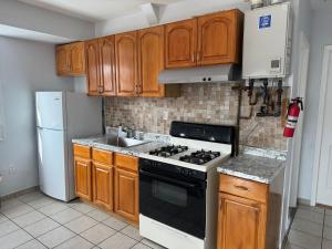 a kitchen with wooden cabinets and a stove and refrigerator at Cozy apartment nexttomain st in Passaic