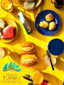 einen gelben Tisch mit Platten aus Gebäck und Obst in der Unterkunft Pousada Tupaiú in Alter do Chao