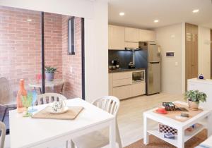 cocina y sala de estar con mesa blanca y sillas en The Petit Flat - Bright & stylish studio apartment near Unicentro, en Bogotá