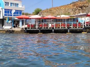 a restaurant with red chairs and umbrellas on the water at Suite Big Lanche in Praia Baixo