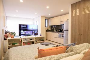 a living room with a couch and a tv in a kitchen at The Petit Flat - Bright & stylish studio apartment near Unicentro in Bogotá