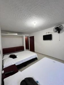 a bedroom with two beds and a flat screen tv at Hotel San Cayetano in Ocaña