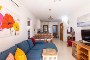 Una sala de estar con un sofá azul y un comedor. en Marina d'Or III - Villa 10, en Santanyí