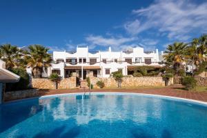 a swimming pool in front of a large white house at Marina d'Or III - Villa 10 in Santanyi