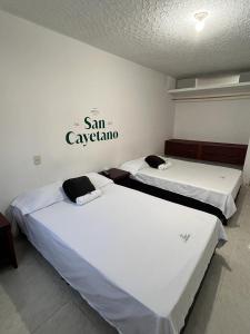 2 camas en una habitación con un cartel en la pared en Hotel San Cayetano en Ocaña