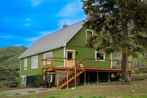 una casa verde con terrazza e albero di Triumph Ranch Farm House ad Hailey