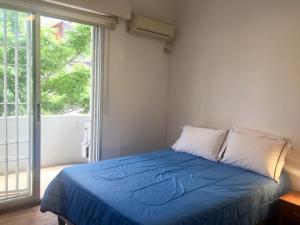 um quarto com uma cama azul e uma grande janela em Artistes du Monde em Montevidéu