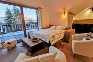 sypialnia z łóżkiem i krzesłami oraz dużym oknem w obiekcie Magnifique appartement au pied des pistes - Le trelod w mieście La Feclaz