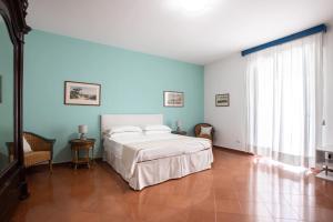 1 dormitorio con 1 cama blanca y paredes azules en Charming bedroom in Sorrento with balcony, en Sorrento