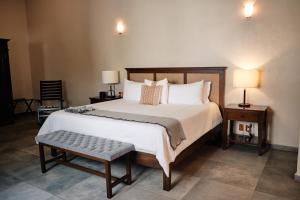a bedroom with a large bed with a bench and two lamps at Casa Lucila Hotel Boutique in Mazatlán