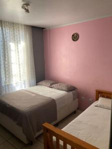 1 dormitorio con 2 camas y pared de color rosa en Hostel do Lucca en Porto Alegre