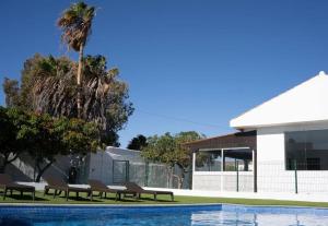 una piscina con sillas junto a un edificio en Villa Mirador de los Abrigos, en La Mareta