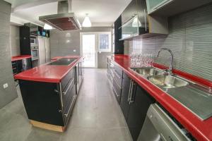 cocina grande con encimeras rojas y lavabos en Villa Mirador de los Abrigos, en La Mareta