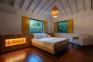 a bedroom with a bed and a couch and two windows at Carmo Country Villas in Ponta Delgada