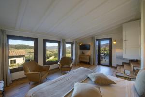 a bedroom with a large bed with chairs and windows at My Exclusive Italy - Villa Chianti with infinity pool and vineyard view in Greve in Chianti