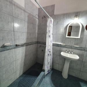 uma casa de banho com uma cortina de chuveiro e um lavatório em GUDIVAMA. em Las Grutas