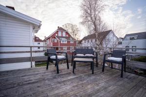tre sedie su una terrazza di legno con edifici sullo sfondo di City Center Getaway 9 by Berti a Stavanger