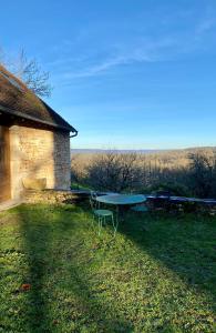 a picnic table in the grass next to a building at La Grangette de Paunac in Cazillac
