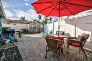a patio with a table and chairs with a red umbrella at Beautiful Waterfront Beach Cottage. Sleeps 6 in Clearwater Beach