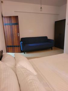 um quarto com uma cama e um sofá azul em M-stay Colombo em Sri Jayewardenepur- Kotte