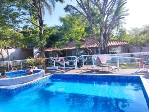 a pool at a resort with people sitting on chairs at Casa de praia Guarau in Peruíbe