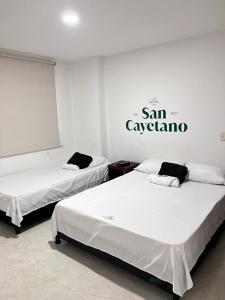 dwa łóżka w pokoju z napisem na ścianie w obiekcie Hotel San Cayetano w mieście Ocaña