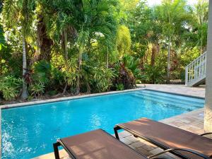 een zwembad met een tafel en stoelen en palmbomen bij Magnolia Breeze in Anna Maria