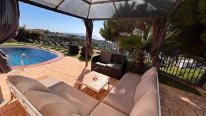 eine Terrasse mit einem Sofa, einem Stuhl und einem Pool in der Unterkunft Luxury Villa Marina in Lloret de Mar