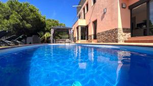 a large blue swimming pool next to a building at Luxury Villa Marina in Lloret de Mar