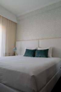 a bedroom with a large white bed with green pillows at Belem Hotel in Pombal