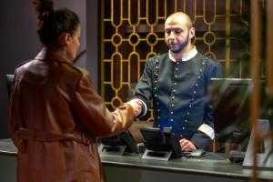 una mujer estrechando la mano con un hombre en un mostrador en Twenties Hotel, en Tiflis