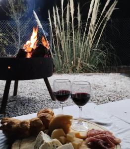 two glasses of red wine next to a fire pit at Casa de Balsa in Neuquén